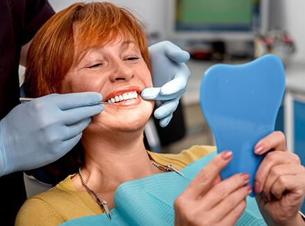 woman examining her smile in a mirror